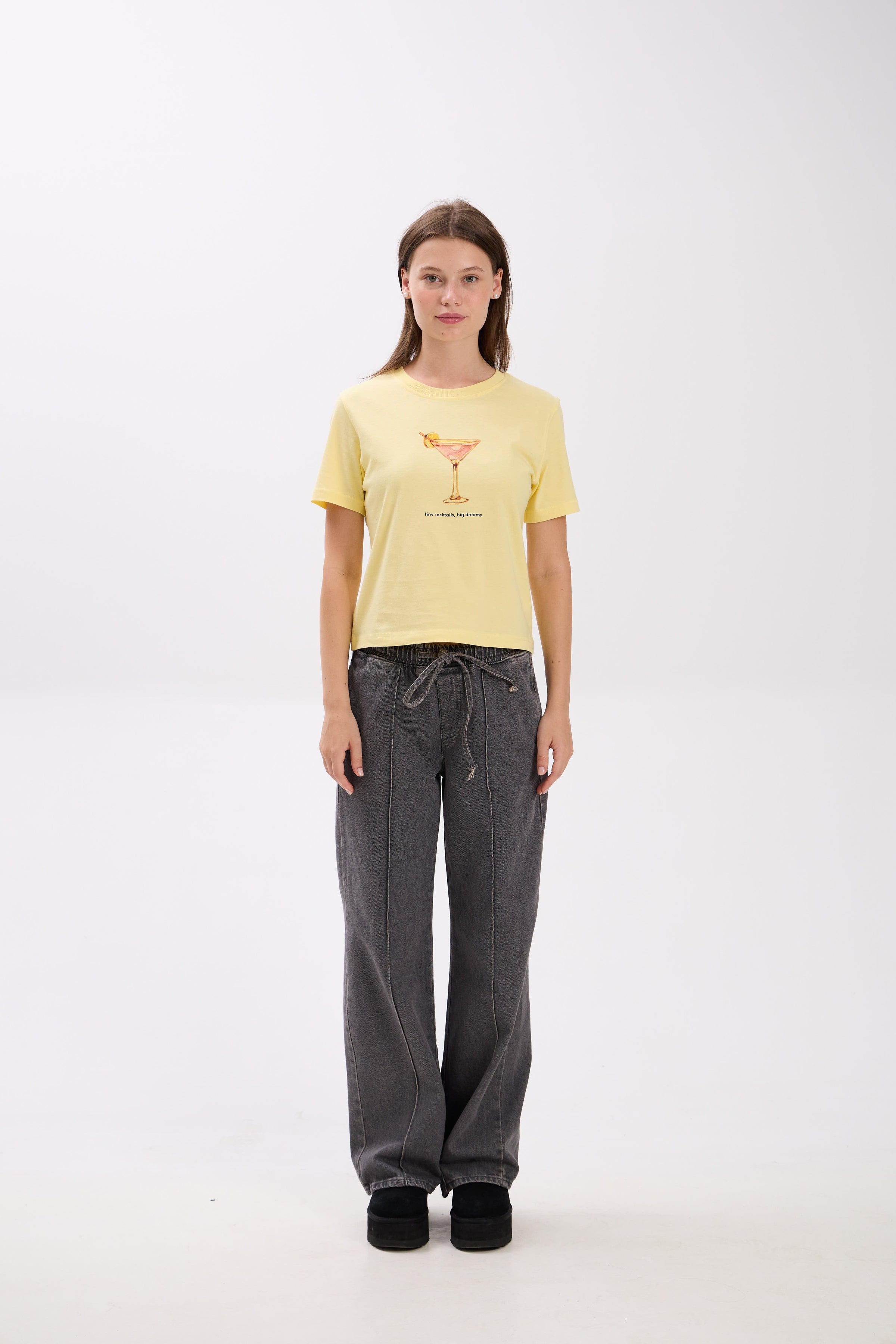 Person wearing a yellow t-shirt and gray pants on a white background.