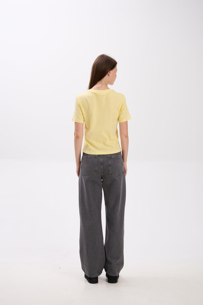 Person wearing a yellow top and gray pants on a white background.