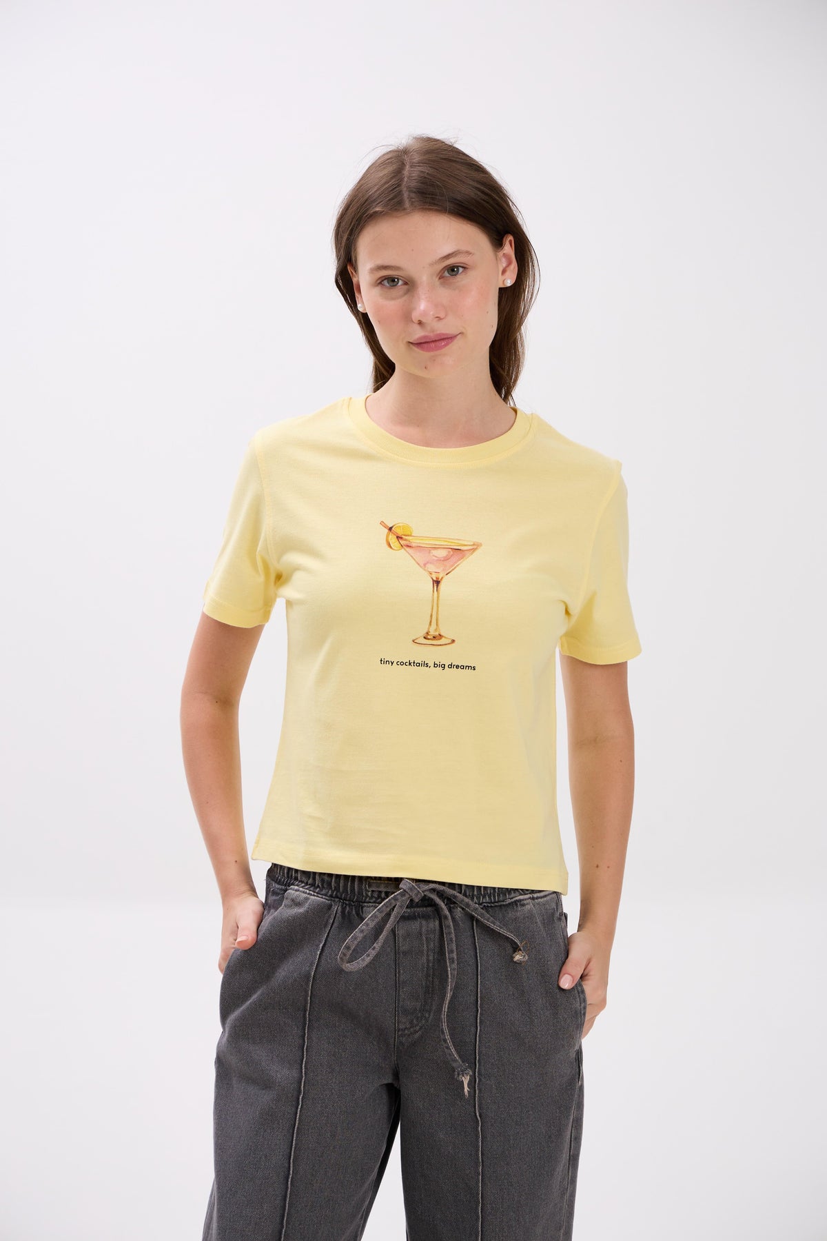 Woman wearing a yellow t-shirt with a graphic design on a white background.