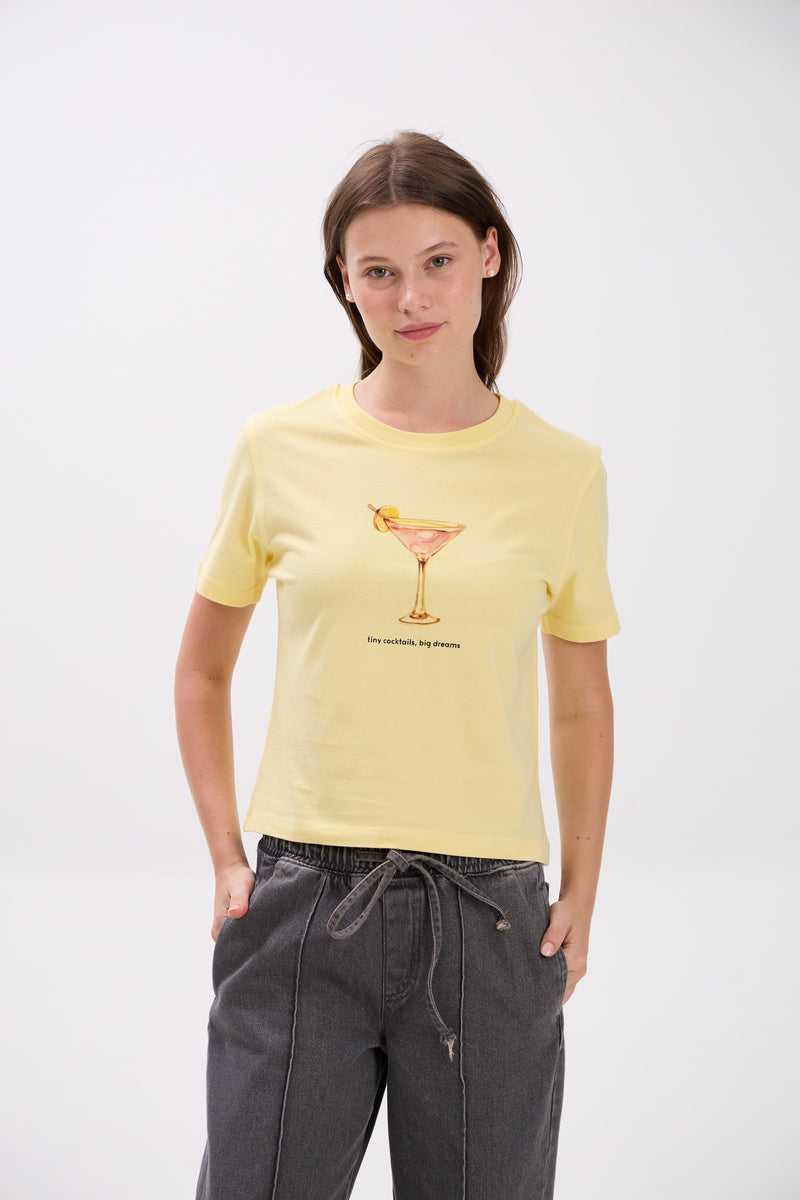 Woman wearing a yellow t-shirt with a graphic design on a white background.