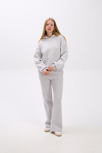 Person wearing a gray hoodie and pants on a white background.