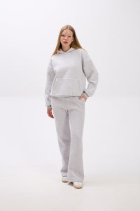 Person wearing a gray tracksuit on a white background.
