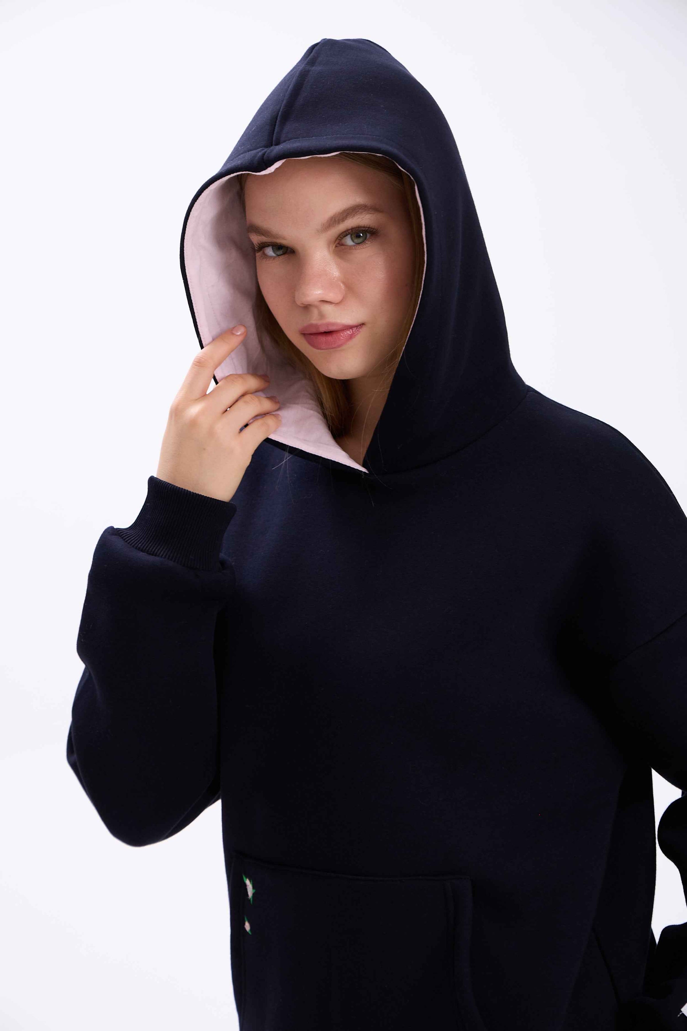 Person wearing a black hoodie with a white interior lining on a white background.