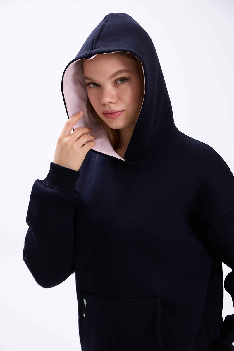 Person wearing a black hoodie with a white interior lining on a white background.