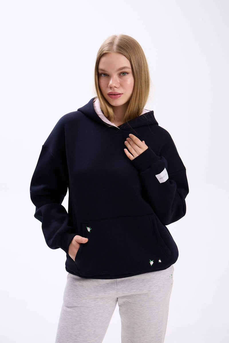 Woman wearing a navy blue hoodie with white accents on a white background.