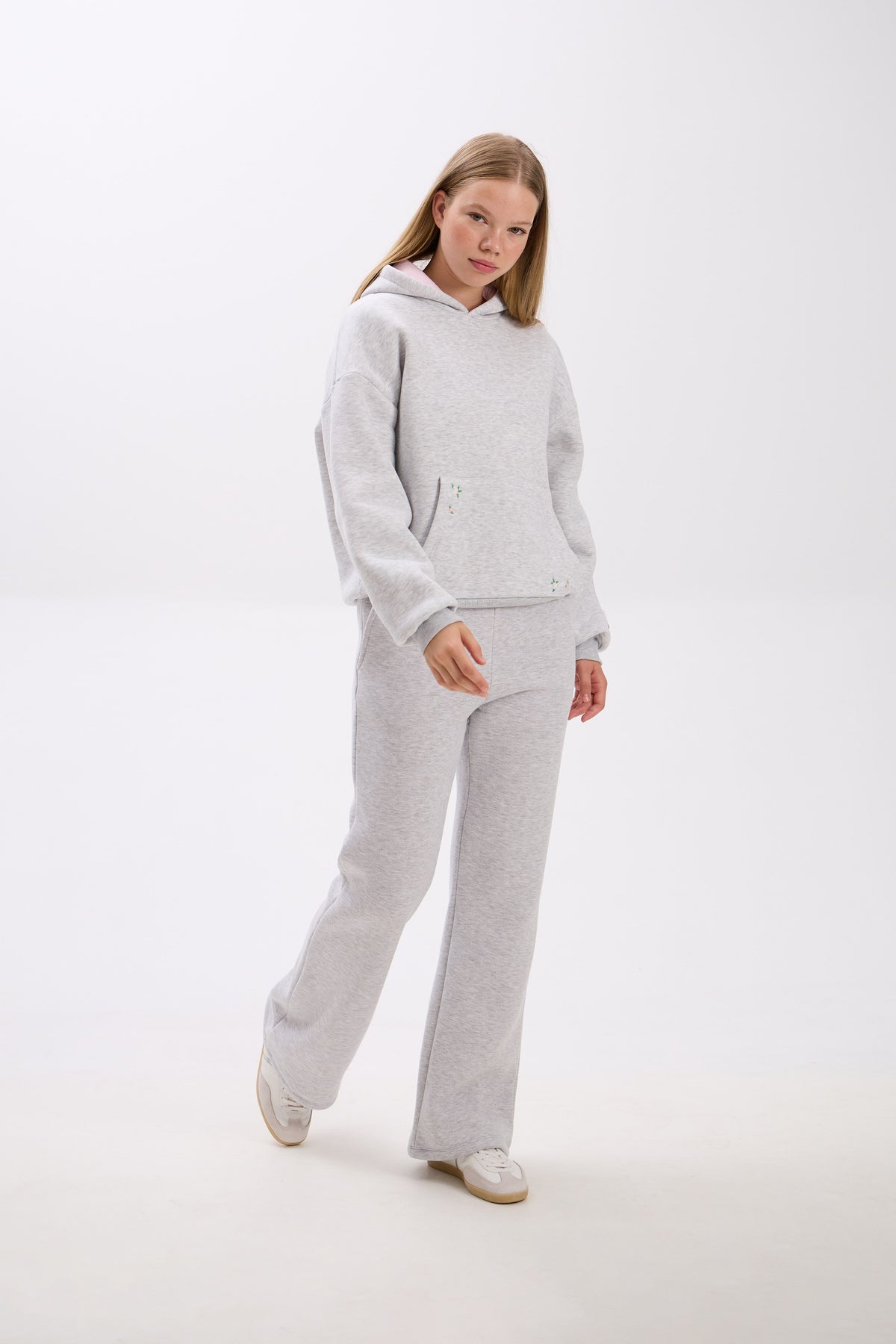 Person wearing a gray tracksuit on a white background.