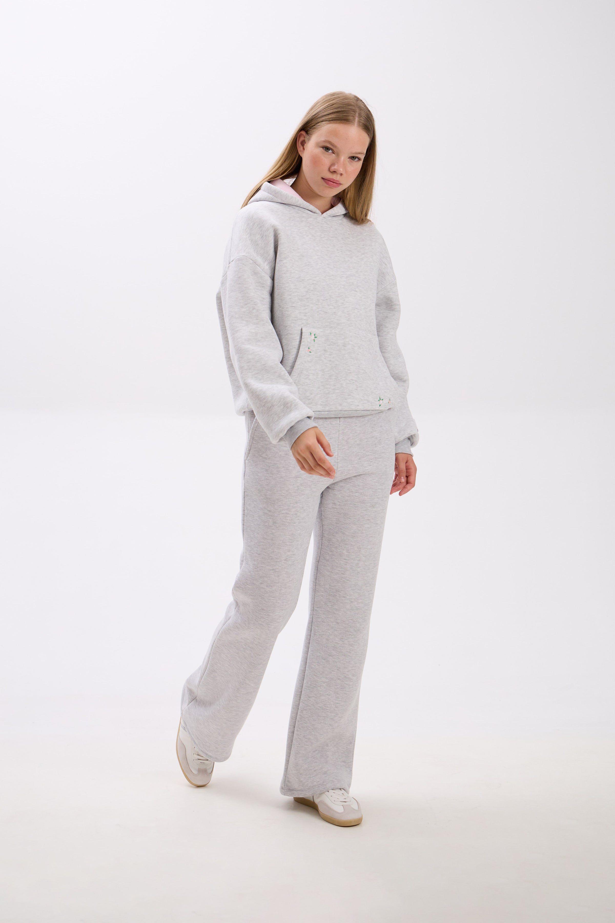 Person wearing a gray tracksuit on a white background.