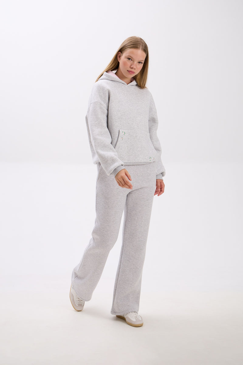 Person wearing a gray tracksuit on a white background.