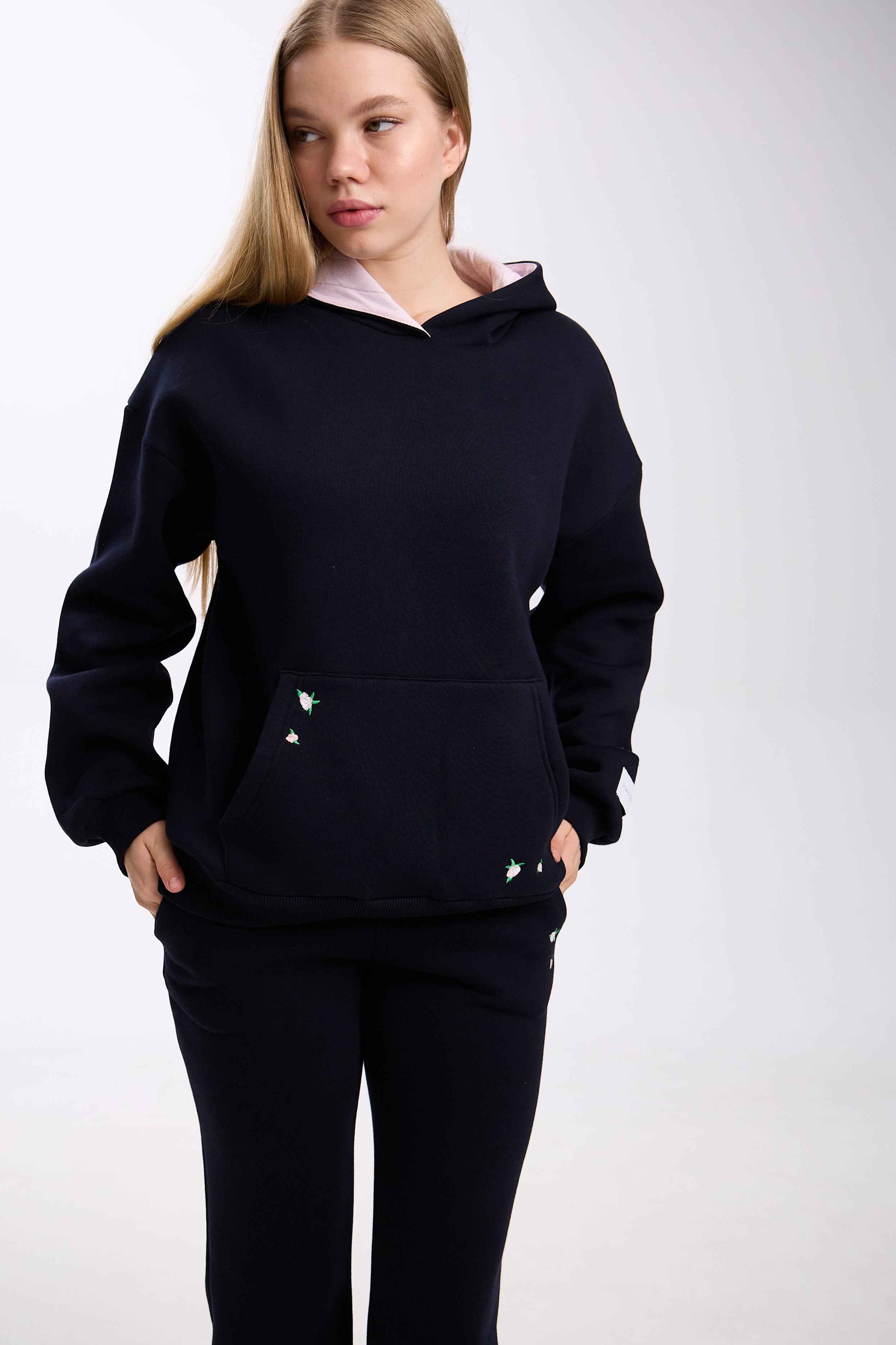 Person wearing a black hoodie and pants on a white background.