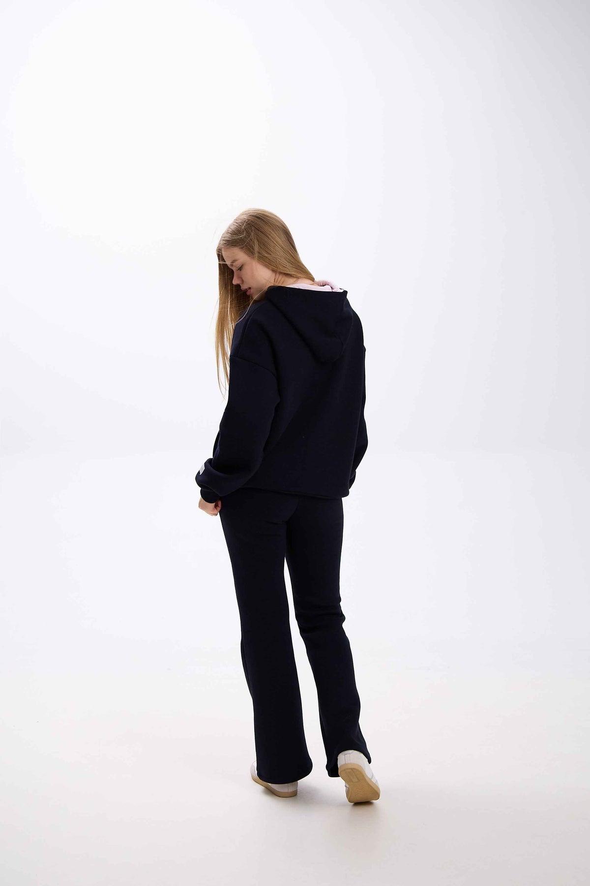 Person wearing a black hoodie and pants on a white background.