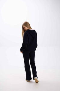 Person wearing a black hoodie and pants on a white background.