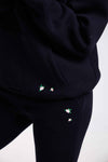 Black hoodie and pants with small embroidered designs on a white background.