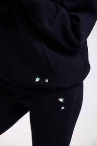 Black hoodie and pants with small embroidered designs on a white background.
