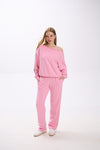 Model in a pink off-shoulder sweatshirt with logo sleeve detail, paired with matching pink sweatpants and sneakers.