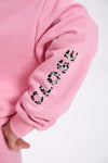 Close-up of pink sweatshirt sleeve with leopard print “CLOSE” text detail.