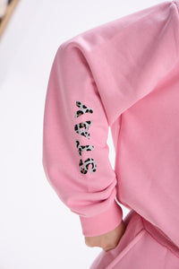 Close-up of pink sweatshirt sleeve with leopard print “STAY” text detail.