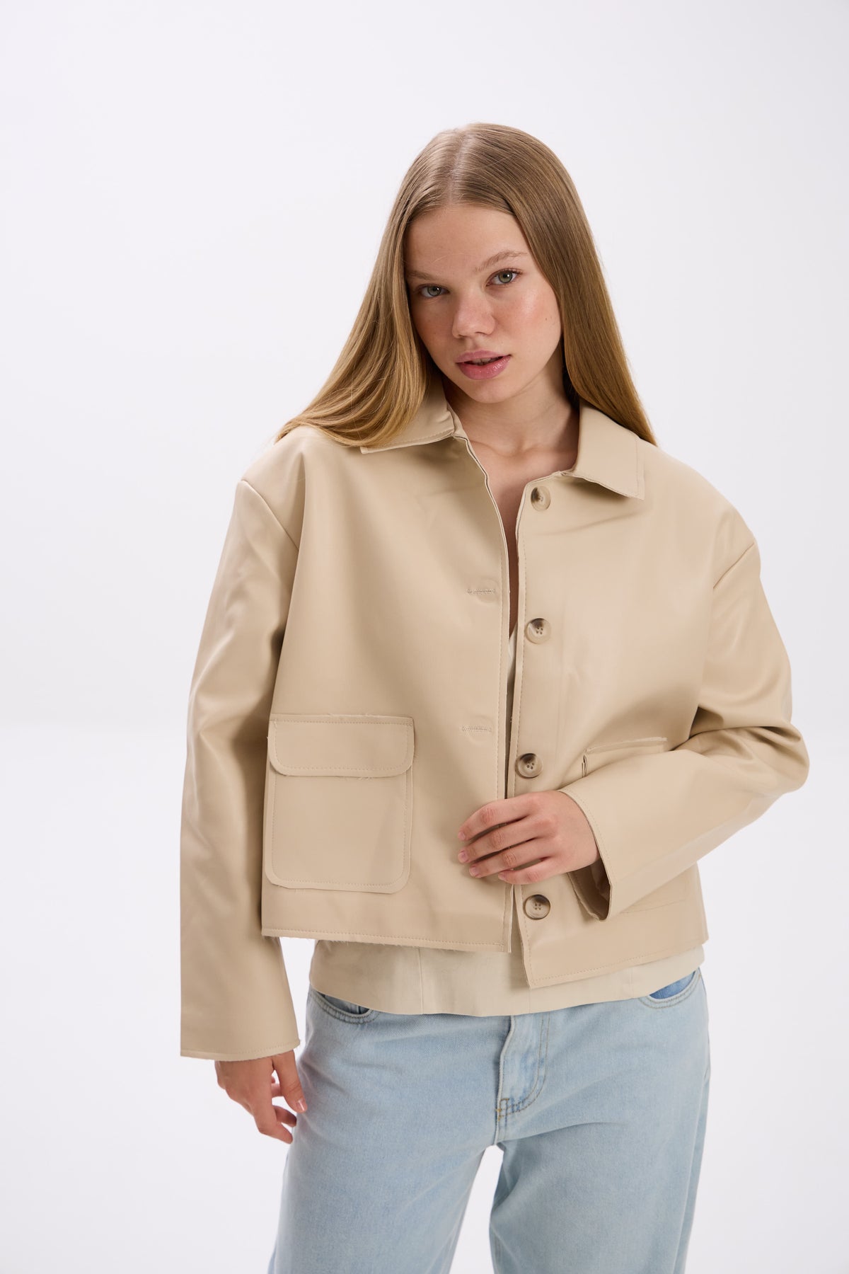 Woman wearing a beige jacket on a white background.