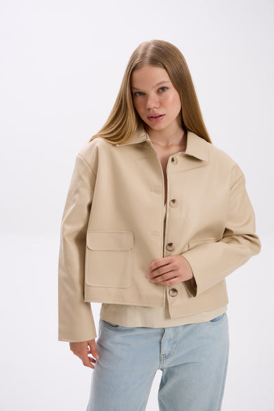 Woman wearing a beige jacket on a white background.