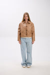Person wearing a tan jacket and light blue jeans on a white background.