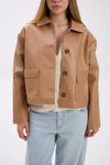 Person wearing a tan leather jacket with a white background.