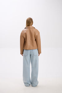 Person wearing a brown leather jacket and light blue jeans on a white background.