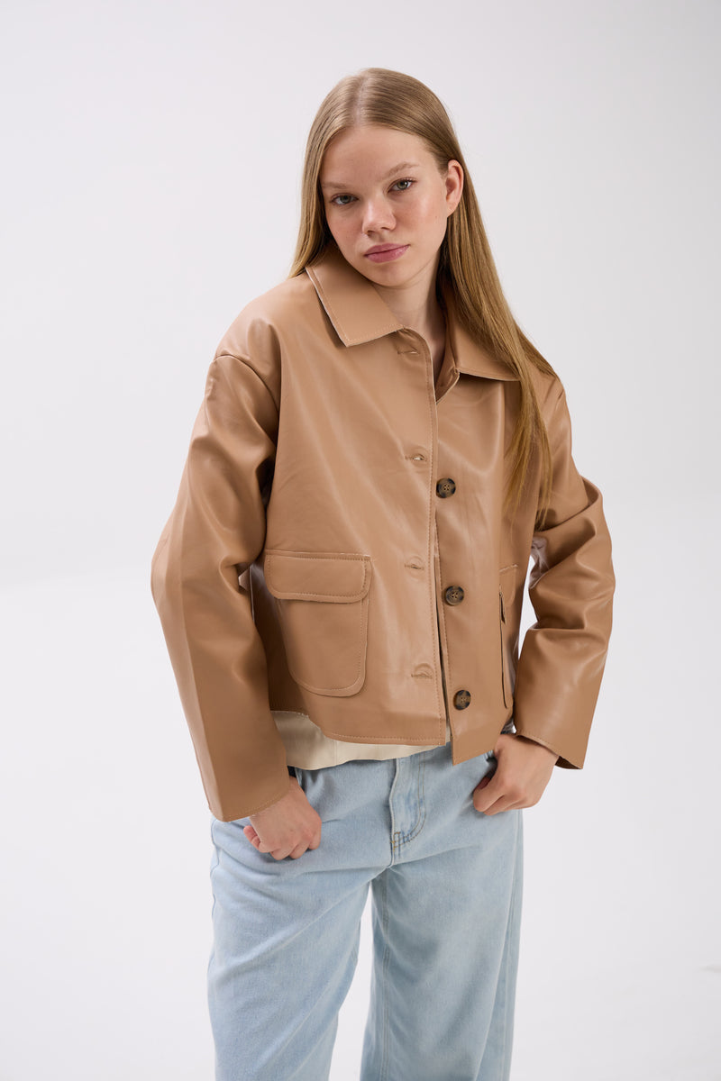Woman wearing a beige jacket and light blue jeans on a white background.