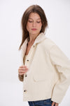 Woman wearing a cream-colored jacket on a white background.