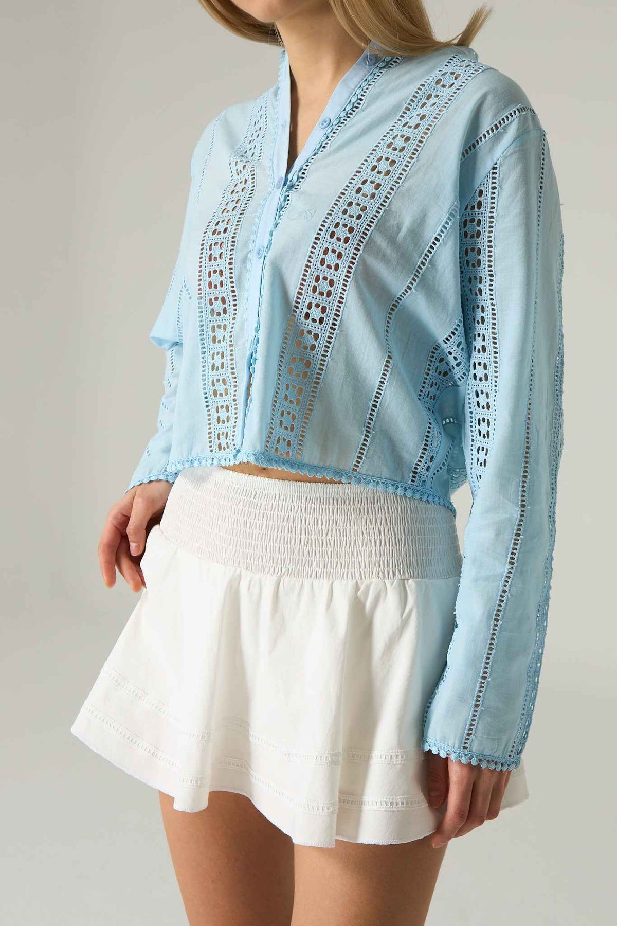 Light blue embroidered top with a white skirt on a plain background.