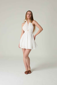 Woman wearing a white dress against a plain background.