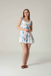 Woman wearing a floral dress on a plain background.