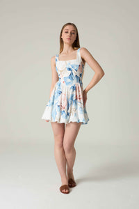 Woman wearing a floral dress on a plain background.