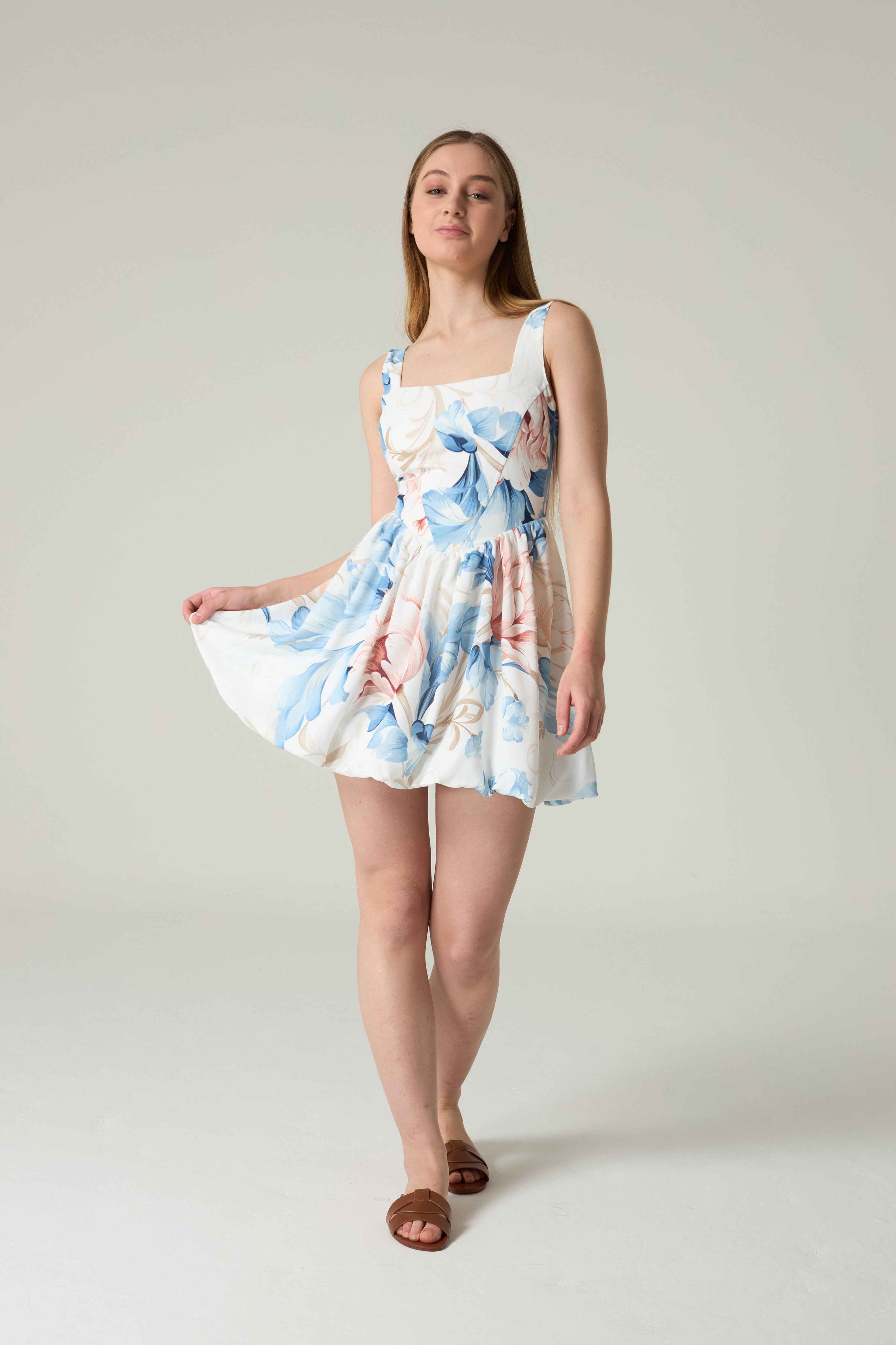 Woman wearing a floral dress on a plain background.