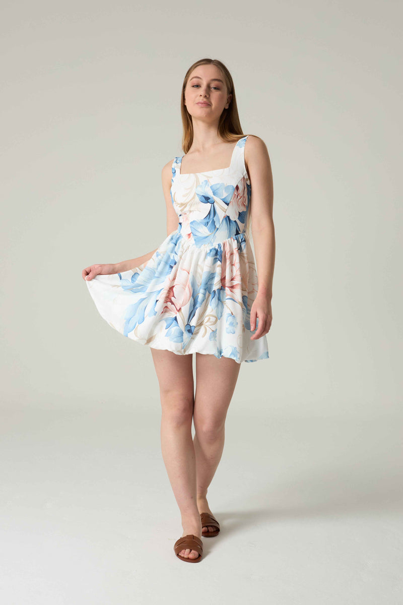 Woman wearing a floral dress on a plain background.