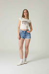 Person wearing a white crop top with 'Arizona' text and denim shorts on a plain background.