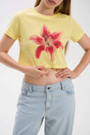 Person wearing a yellow t-shirt with a red floral design and light blue jeans on a white background.