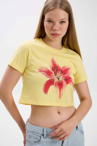 Person wearing a yellow crop top with a red floral design on a white background.
