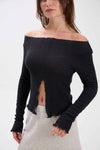 Woman wearing a black off-shoulder knit top with a white background.