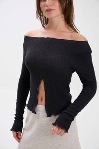 Woman wearing a black off-shoulder knit top with a white background.
