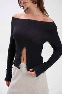 Woman wearing a black off-shoulder sweater and gray skirt on a white background.