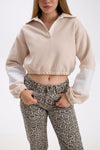Person wearing a beige and white cropped sweatshirt with leopard print pants on a white background.
