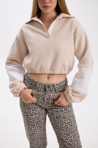 Person wearing a beige and white cropped sweatshirt with leopard print pants on a white background.