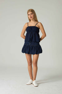 Woman wearing a navy blue dress on a white background.