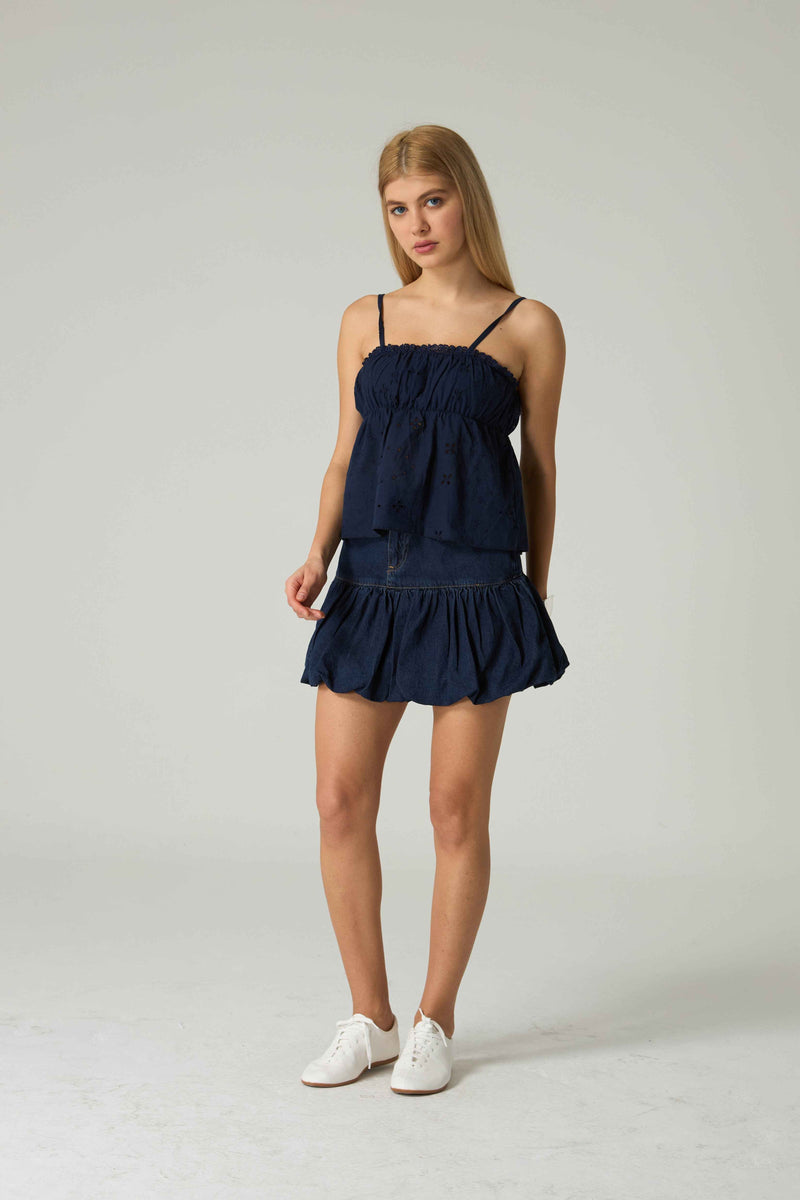 Woman wearing a navy blue dress on a light gray background.