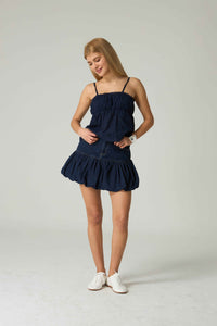 Woman wearing a navy blue dress on a plain background.