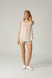 Woman wearing a beige sleeveless top and shorts on a white background.