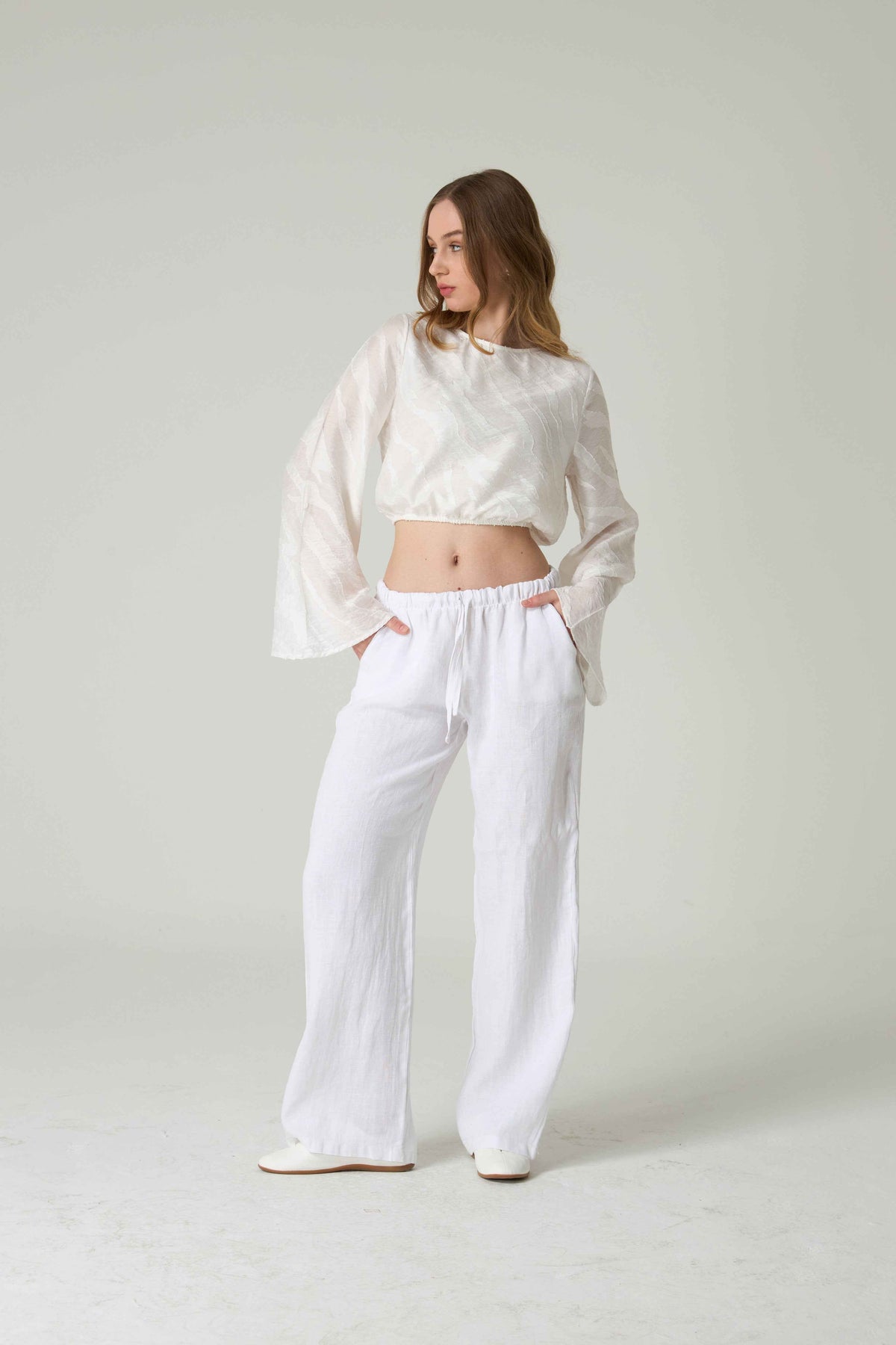 Woman wearing a white outfit with a plain background.