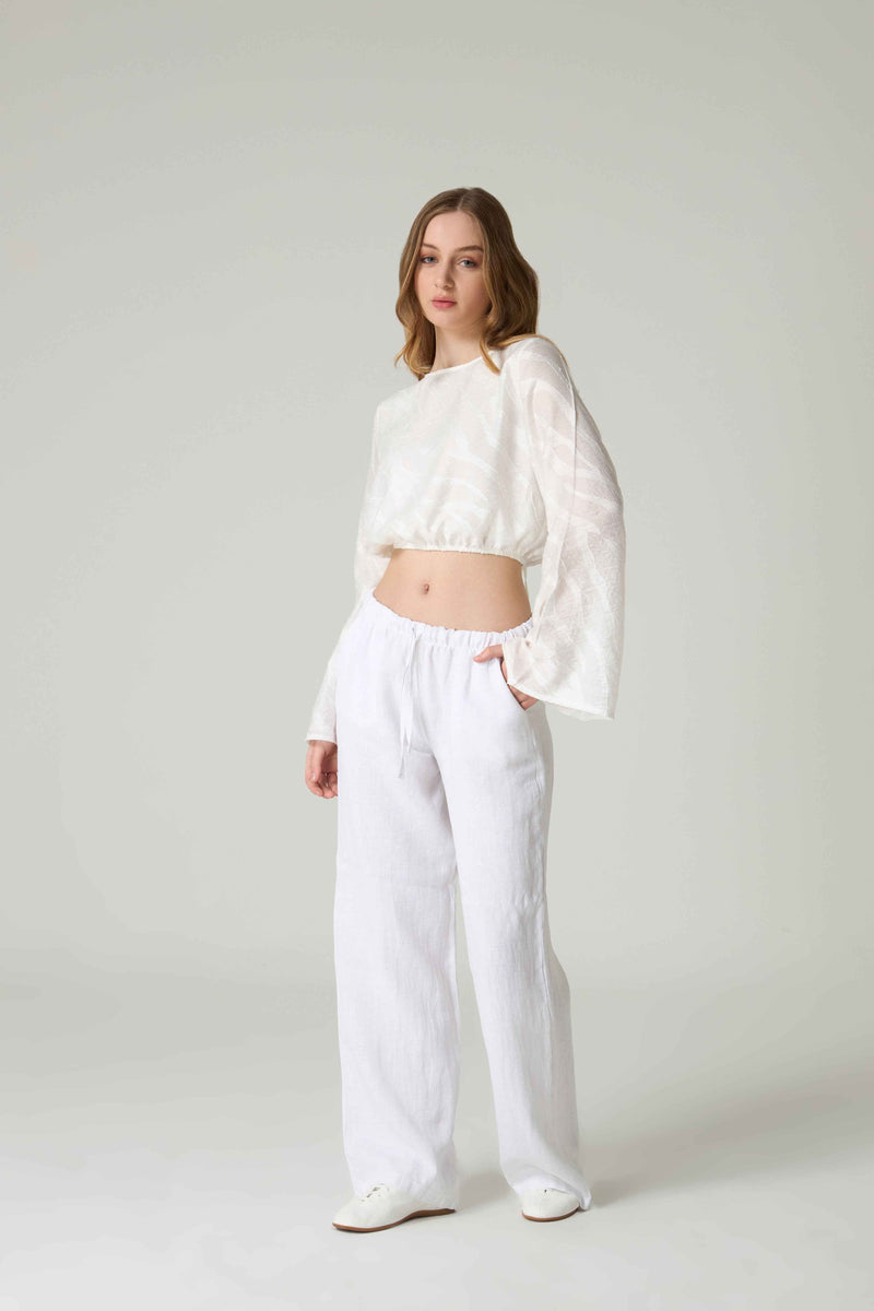 Woman wearing a white outfit on a plain background.