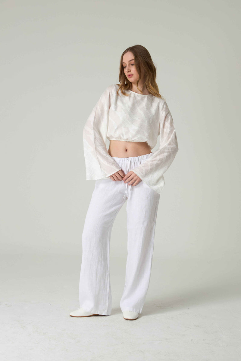 Woman wearing a white outfit with a plain background.