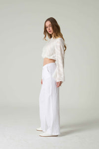 Woman wearing a white outfit on a plain background.