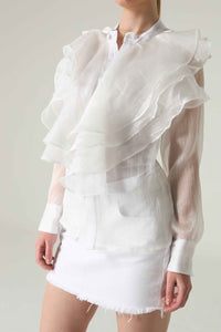White ruffled blouse and skirt set on a plain background.